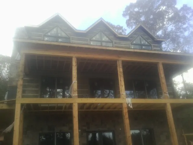Dormers and porch framing on a large log home under construction — Roof Coating work by our crew in Tuscarora