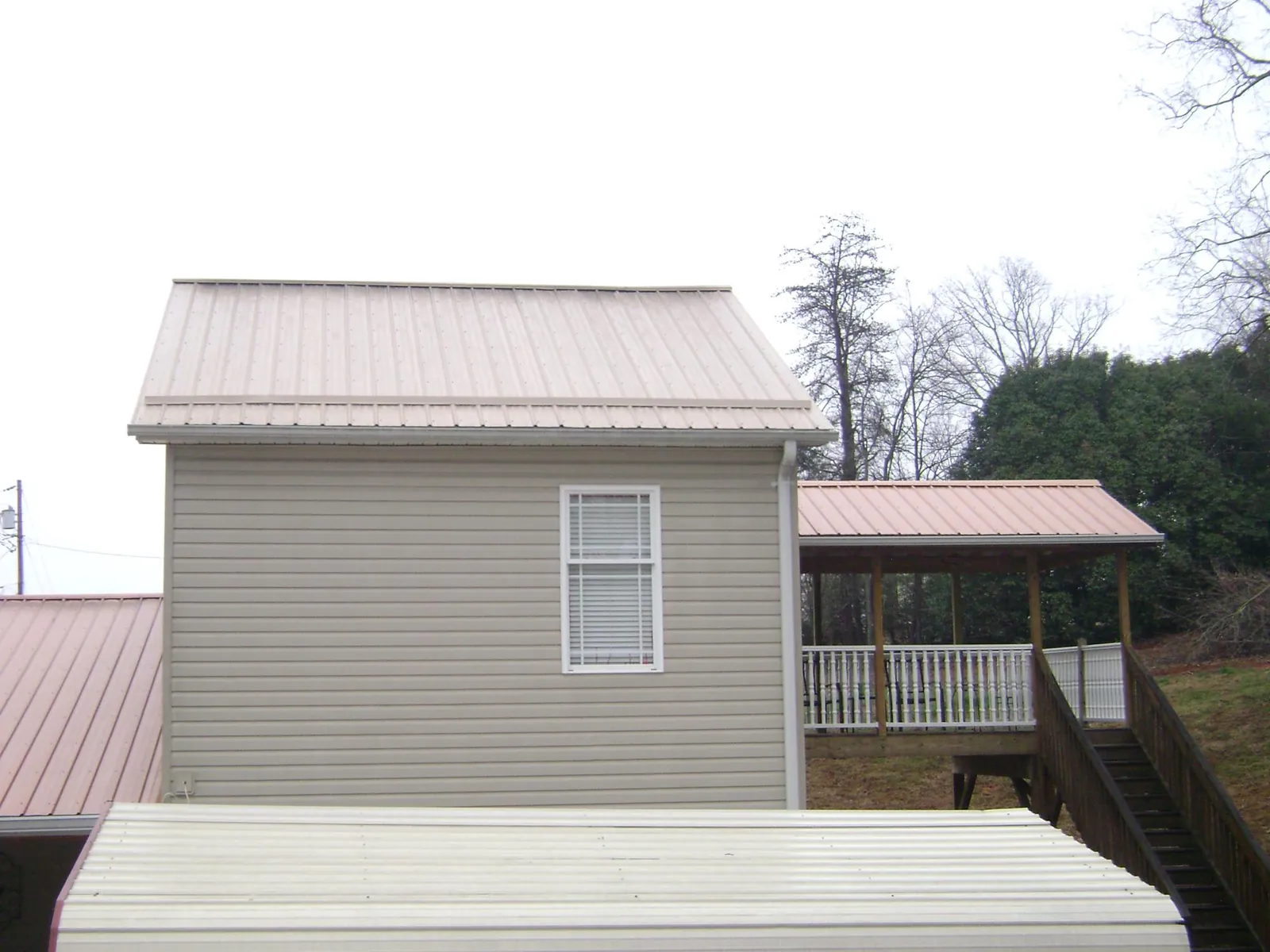 Tan metal roofs on a two story addition and attached porch, from a Roof Replacement job in Tuscarora